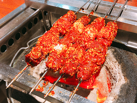 名物の羊肉の串焼きをテーブルの炭火で自分たちで焼いて食べられる